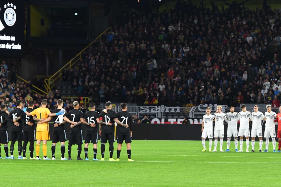 Während einer Schweigeminute zum Gedenken an die Opfer in Halle vor dem Anpfiff des Spieles stehen die Spieler von Argentinien und Deutschland am Anstoßkreis.