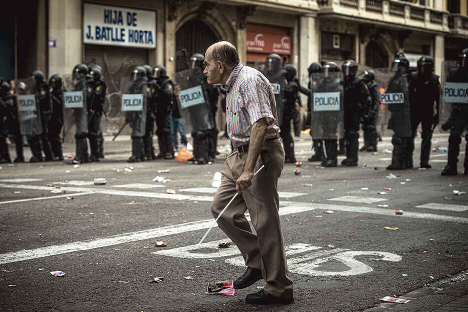 Ein Mann geht während einer Demonstration in Bracelona an einer Barrikade von Polizisten vorbei.
