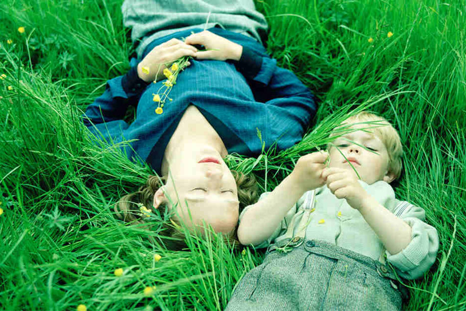 Astrid Lindgren (Alba August) entspannt mit ihrem Sohn Lasse (Marius Damslev) im Gras.