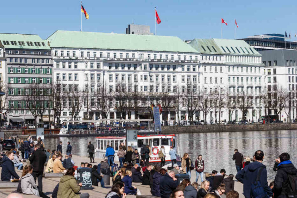 Zahlreiche Menschen sitzen bei Sonnenwetter an der Alster in Hamburg. Hier wollen am Dienstag Beschäftigte im öffentlichen Dienst aus Protest baden gehen.