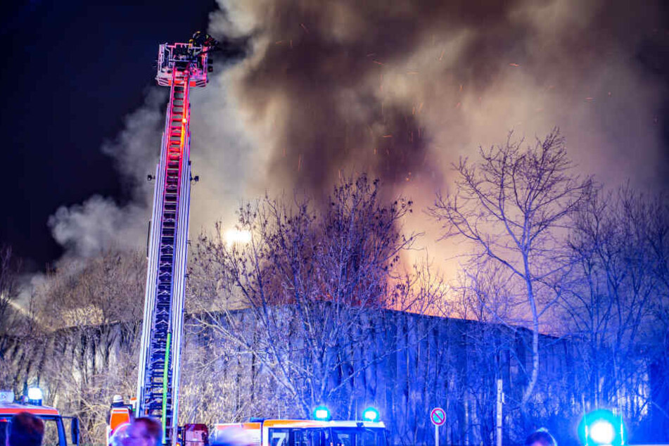 Feuerwehrleute löschen eine brennende Lagerhalle auf dem Messegelände.