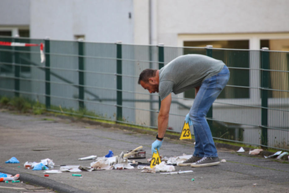 Ein Ermittler der Polizei sichert am Tatort auf einem Gehweg in Hagen Spuren. Hier wurde der 53-Jährige erstochen.