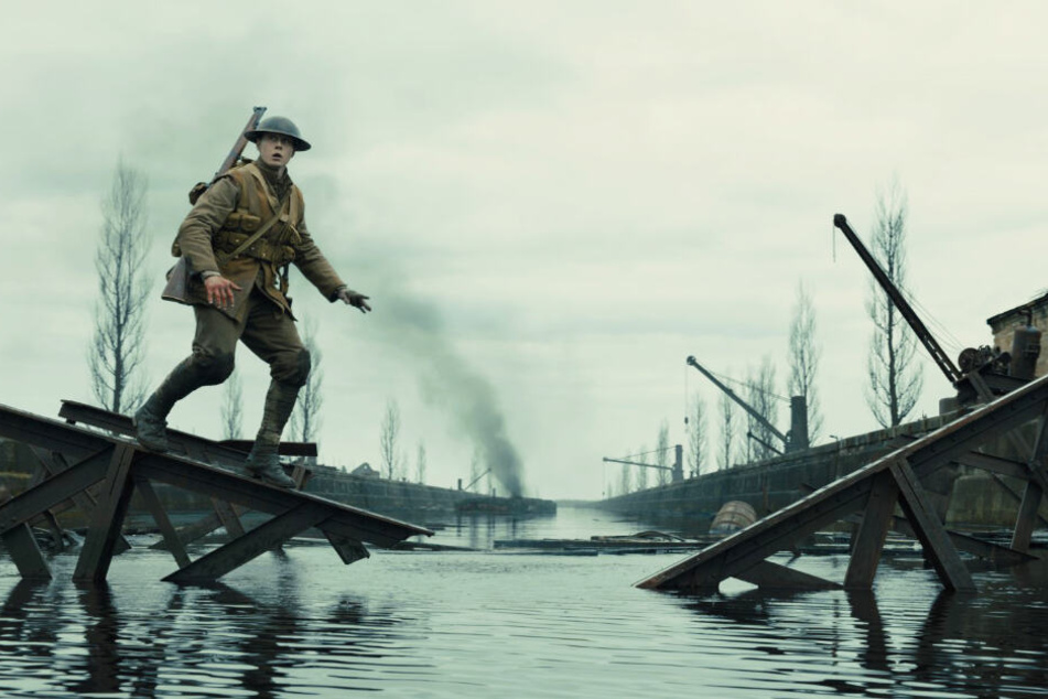 Schofield (George MacKay) balanciert auf einem Geländer einer kaputten Brücke.