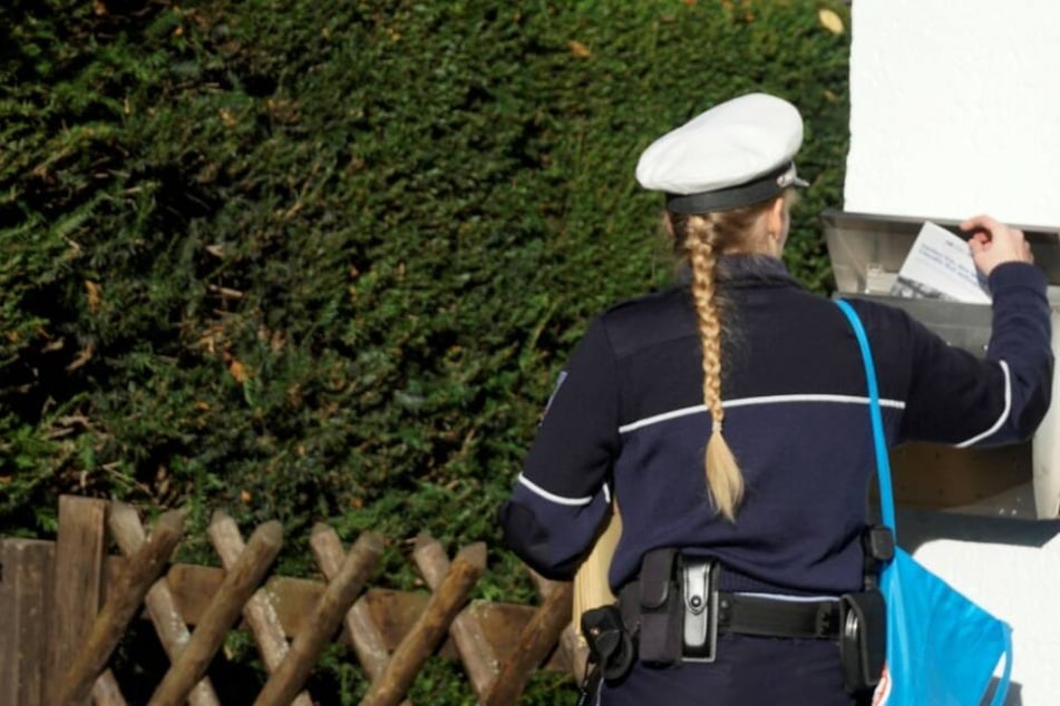 Eine Polizistin informiert Anwohner über den bevorstehenden DNA-Massentest.