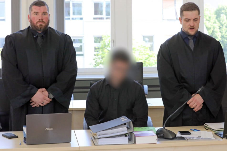 Der Angeklagte sitzt zwischen seinen beiden Verteidigern.