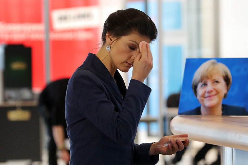 Sahra Wagenknecht, Vorsitzende der Bundestagsfraktion der Partei Die Linke. Hinter ihr auf einem Tisch steht das Portrait der Bundeskanzlerin.