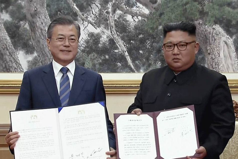 Moon Jae In (l), Präsident von Südkorea, und Kim Jong Un, Machthaber aus Nordkorea, zeigen die unterzeichneten Dokumente.