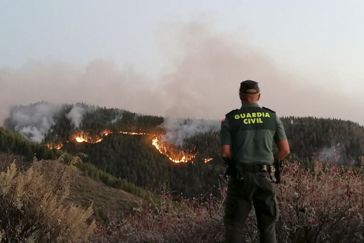 Ein Beamter der Polizei steht vor den Flammen.