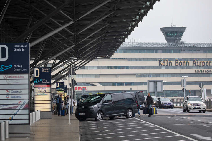 Fluggäste steigen vor dem Terminal des Flughafen Köln/Bonn aus ihren Fahrzeugen.