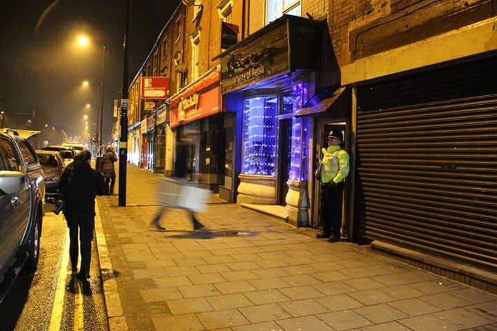 Ein Polizist steht in Birmingham vor einem Wohnhaus. Bewaffnete Polizisten hatten in dem Haus eine Wohnung gestürmt.