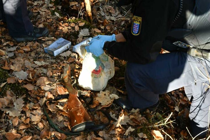 Ein Polizist sammelt die Munition ein, daneben liegt ein Gewehr.