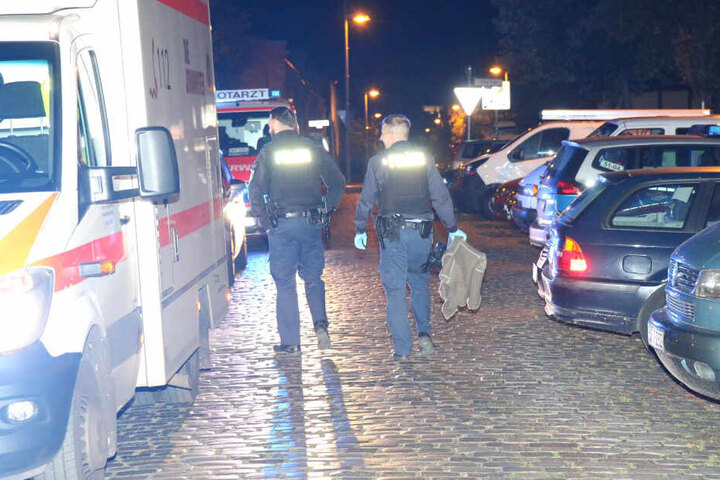 Zwei Polizisten gehen die Straße entlang, der rechte hält eine Wolldecke in der Hand.