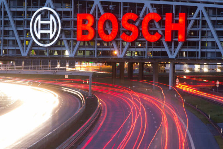 Autos fahren auf der Autobahn 8 unter einer Brücke mit dem Bosch-Logo entlang.