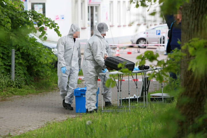 Mitarbeiter der Spurensicherung stehen unweit des Ortes, an dem die Leiche des Tatverdächtigen gefunden wurde.
