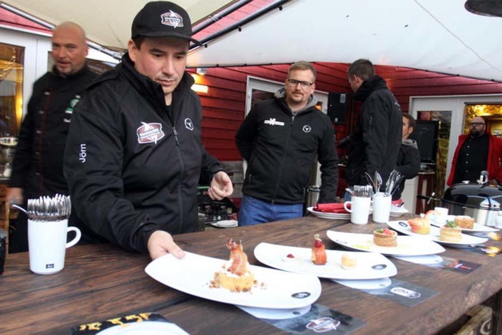 An einem langen Tisch werden die gegrillten Speisen serviert.