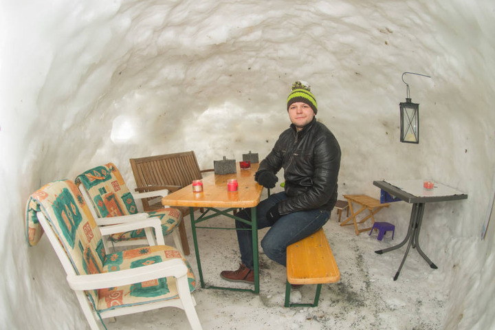 Im Iglu stehen Gartenstühle mit Sitzauflagen, Bänke und ein Bierzelttisch.