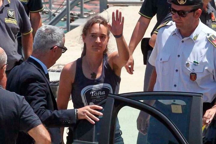 Carola Rackete winkt, als sie nach ihrer Ankunft im Hafen von Porto Empedocle in ein Polizeifahrzeug steigt.