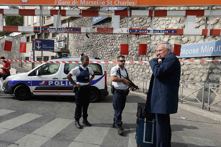 Ein Fahrgast und zwei Polizisten stehen in Marseille vor dem Bahnhof.