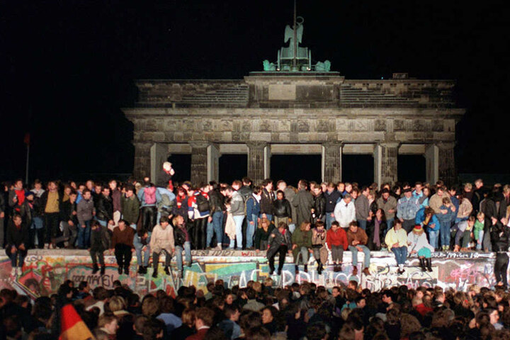 Jubelnde Menschen auf der Berliner Mauer am Brandenburger Tor am 10. November 1989.