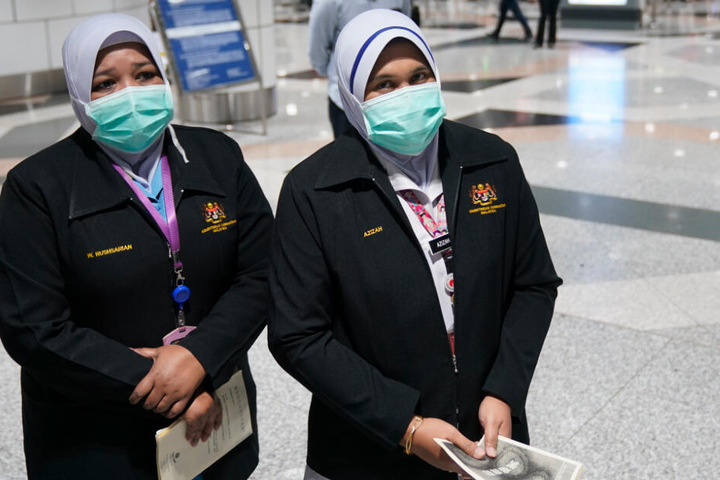 Personal der Gesundheitsbehörde steht mit Mundschutz, als Schutzmaßnahme gegen die Verbreitung der neuartigen Lungenkrankheit durch den Corona-Virus, während einer Inspektion am Flughafen Kuala Lumpur International Airport.