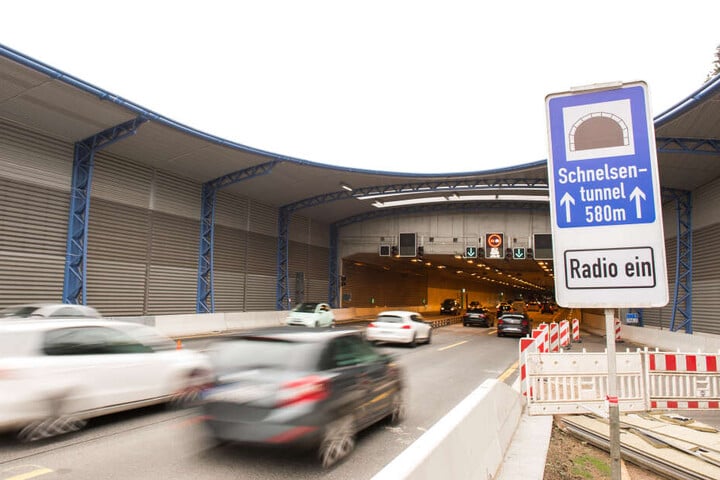 Autos fahren auf der Autobahn 7 in einen Tunnel mit Lärmschutzdeckel.