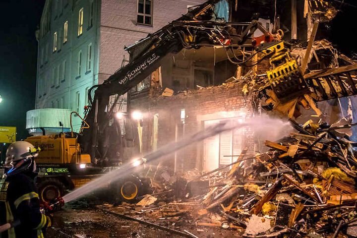 Die Feuerwehr unterstützt die Abrissarbeiten an dem abgebrannten Gebäude.
