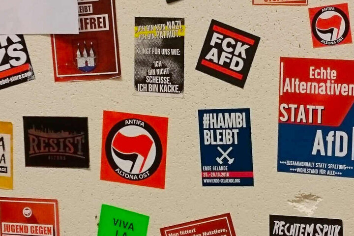 Auf einer Stellwand sind Aufkleber unter anderem von der Antifa Altona Ost und mit AfD-feindlichen Sprüchen angebracht.