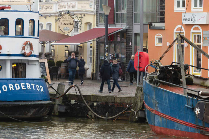 Menschen gehen am Husumer Hafen spazieren.