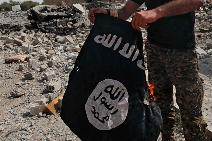 Das Archivbild aus dem Jahr 2017 zeigt eine Fahne des IS, die von einem Kämpfer einer christlich-syrischen Miliz in der syrischen Stadt Al-Rakka verbrannt wird.