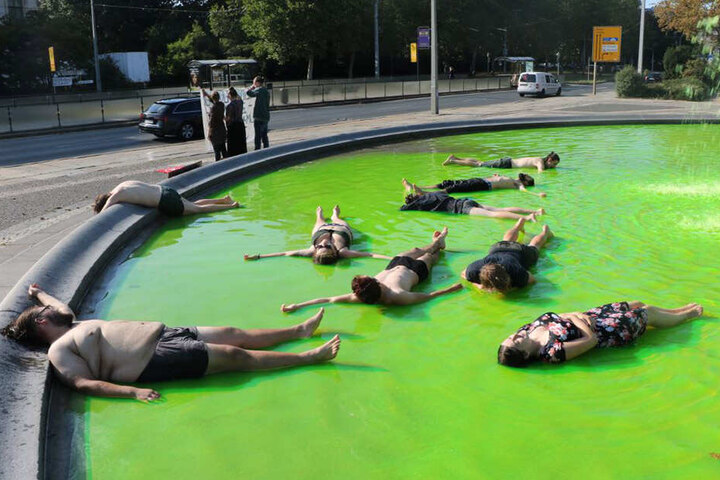 Aktivist/innen liegen im grünfarbenen Wasser. Der Grund: Sie wollen das massive Artensterben infolge der Klimakrise symbolisieren.