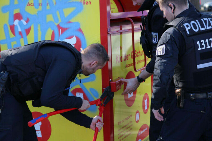 Polizisten brechen die Altkleidercontainer in der Umgebung auf.