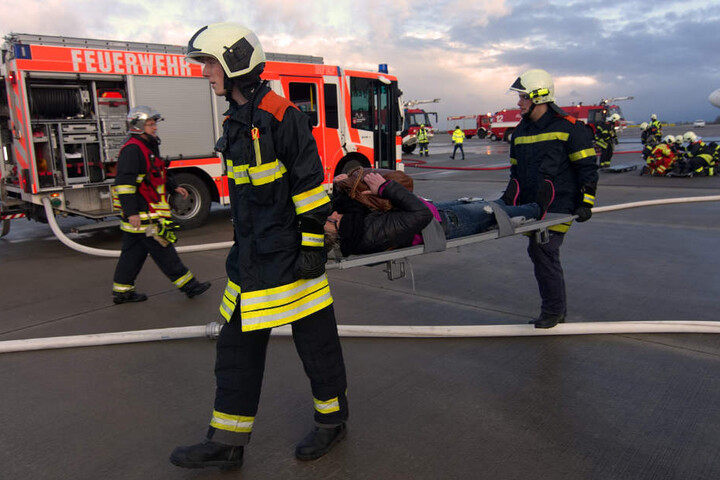 Feuerwehrmänner bringen eine Verletzte zur Patientenablage.