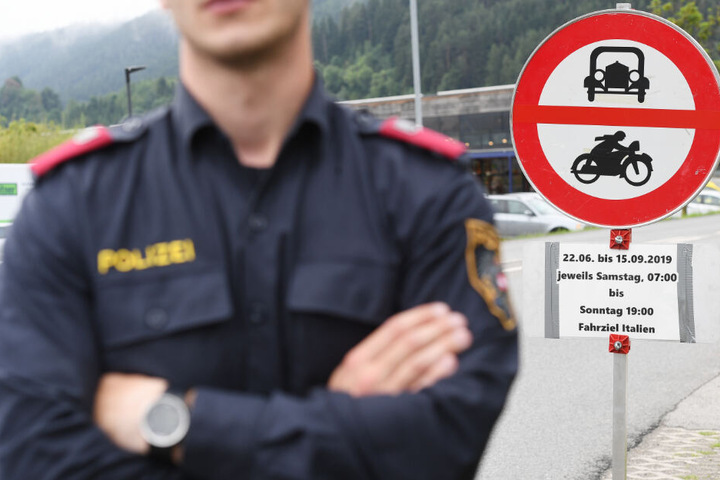 Ein Polizist steht vor einem Schild, das auf die Sperrung für den Verkehr mit Fahrziel Italien hinweißt.