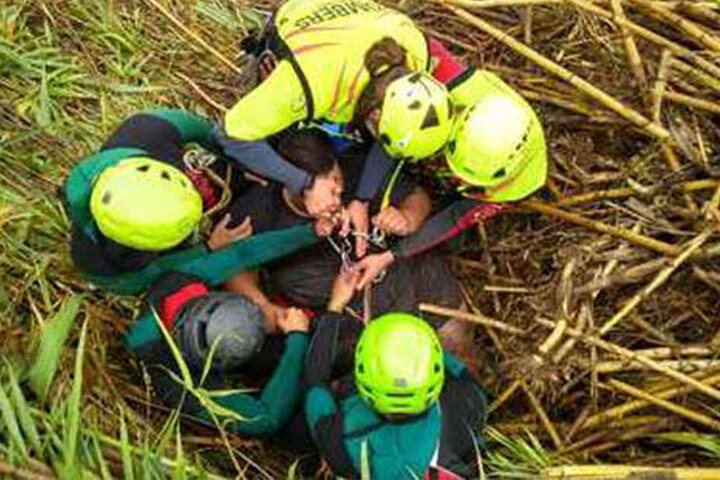 Feuerwehrleute und Beamte der Guardia Civil binden einen Mann mit einem Klettergurt, um ihn aus einem überquellenden Fluss in Canals, Valencia, zu holen.