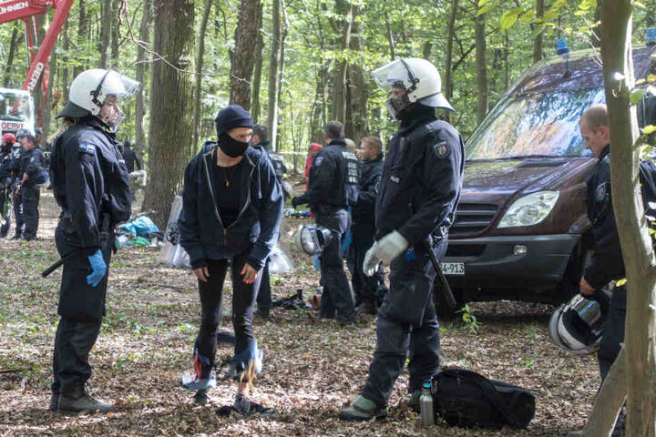 Polizeibeamte mit einem Aktivisten im Wald.