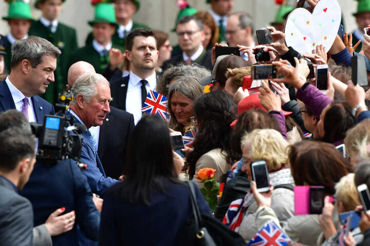 Der britische Thronfolger Prinz Charles (M l) begrüßt die Menschen neben dem bayerischen Ministerpräsidenten Markus Söder (l, CSU) bei seiner Ankunft vor der historischen Residenz auf dem Max-Joseph-Platz.