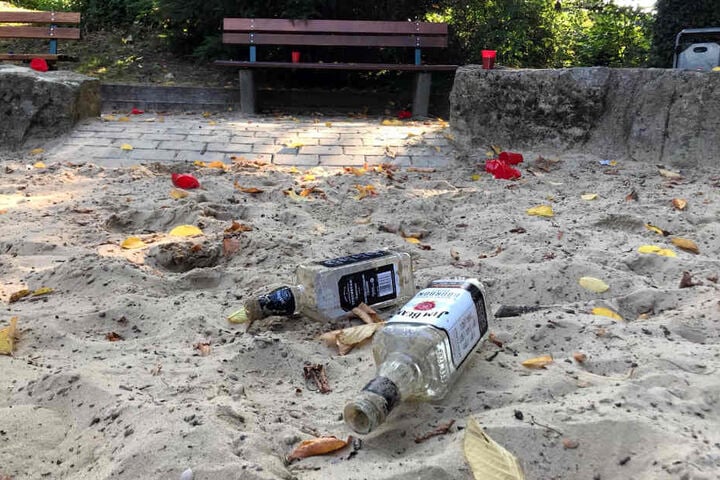 Flaschen und Becher verteilen sich im Sand.