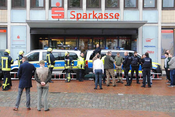 Einsatzkräfte der Polizei und Feuerwehr verbarrikadierten den Eingang einer Sparkassen-Filiale in Heide mit ihren Fahrzeugen.