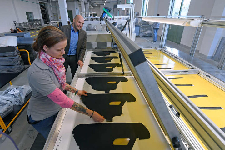 Enja Lang, Mitarbeiterin in der Produktion der C.H. Müller GmbH in Heinsdorfergrund, bestückt einen Nähroboter mit PKW Türverkleidungen an der Seite von Juniorchef Philipp Porst.