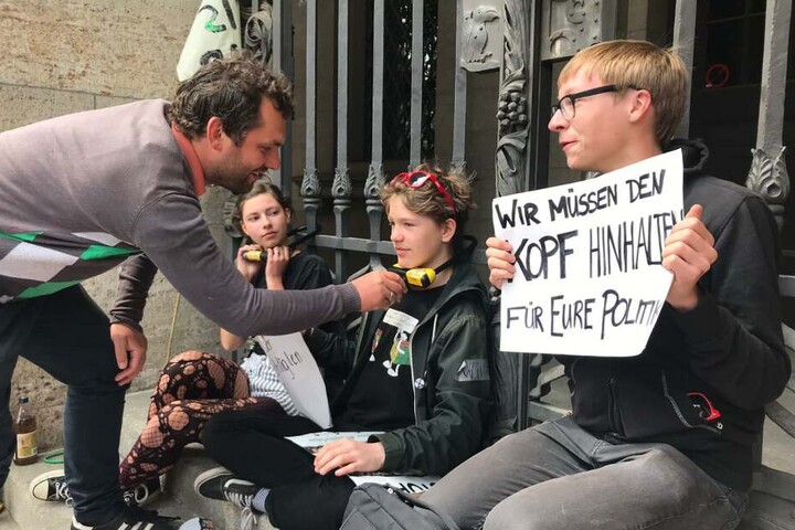 Stadtrat Christopher Zenker von der SPD befreit einen Aktivisten mit dem passenden Schlüssel.