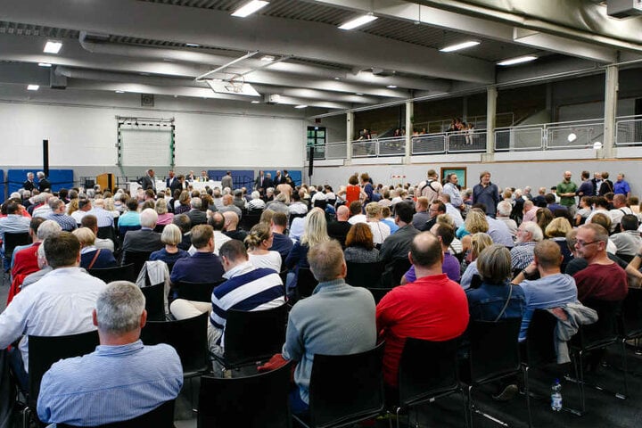 Einwohner der Gemeinde Boostedt sitzen während einer Bürgerversammlung in einer Sporthalle. 