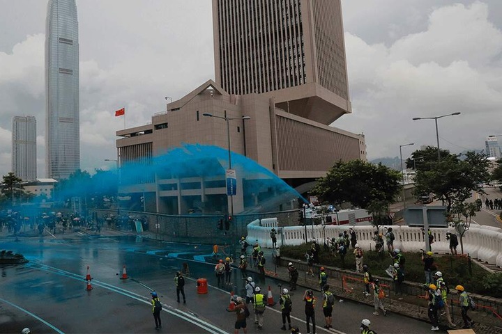 Die Polizei geht mit Wasserwerfern gegen Demonstranten vor und besprüht sie mit blauer Farbe.
