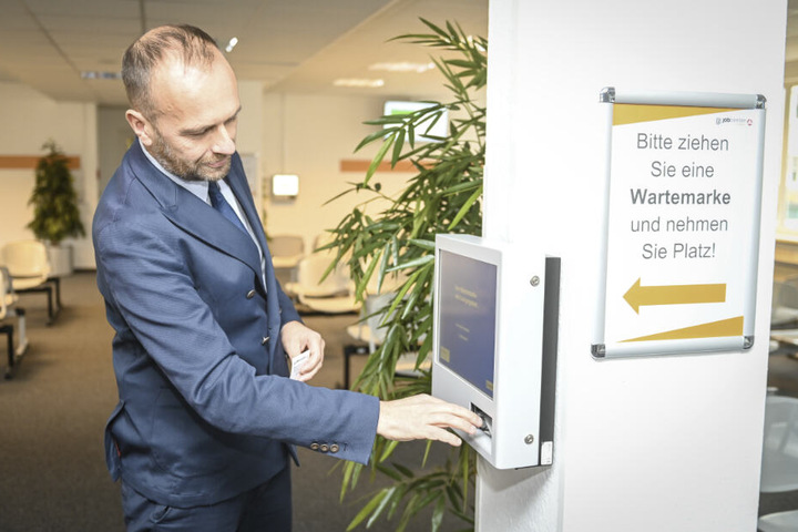 Der Geschäftsführer des Jobcenters Pierre Ullmann (49) testet den neuen Automaten für Wartemarken.