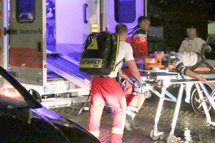 Sanitäter bringen einen verletzten Anwohner ins Krankenhaus.