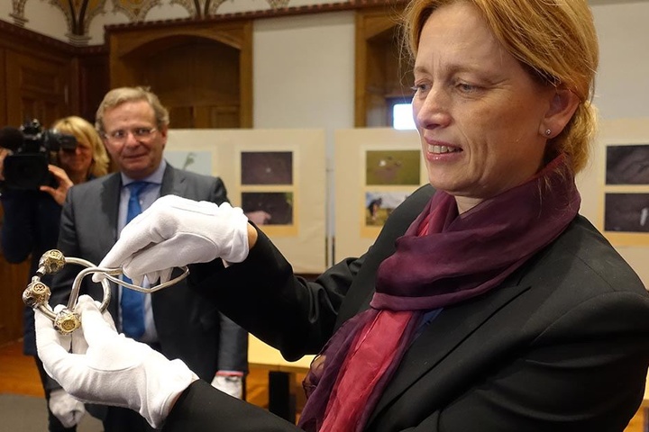 Karin Prien zeigt im archäologischen Landesamt in Schleswig-Holstein eine Ringfibel.