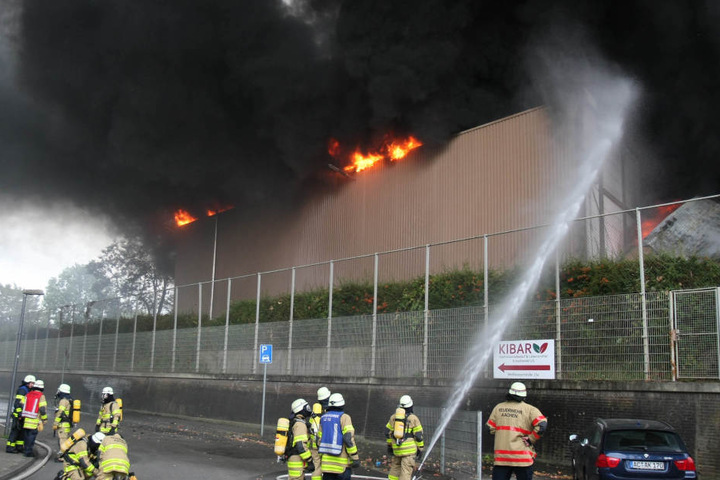 Feuerwehrleute löschen eine Gewerbehalle, in der Elektroschrott in Brand geraten ist.