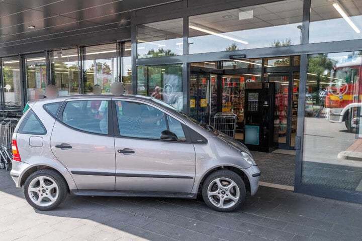 Das Auto steht vor dem Eingang eines Supermarktes.