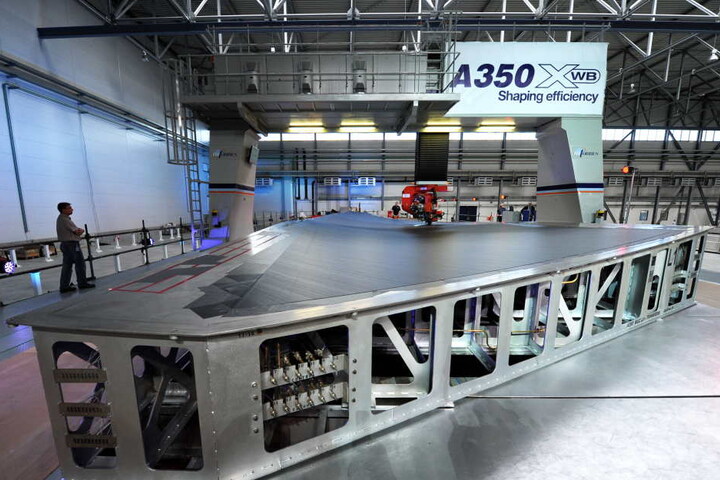 Mit über 32 Metern Länge sind die Tragflächen das größte Bauteil des Airbus A350. Der wird im niedersächsischen Stade montiert, wobei ein Tapeleger (kl.F.) Kohlefaser auf die oberste Flügelschale aufbringt.
