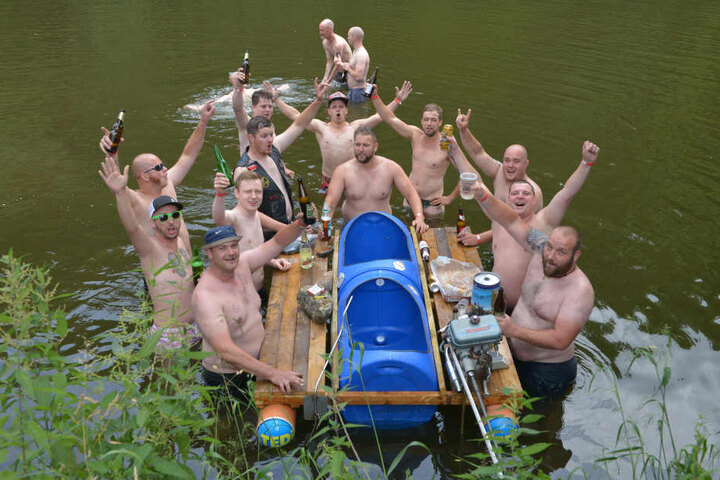 Biker an ihrem selbstgebastelten Tresen-Floß. Das Motorradcamp findet am Zschopau-Ufer statt.