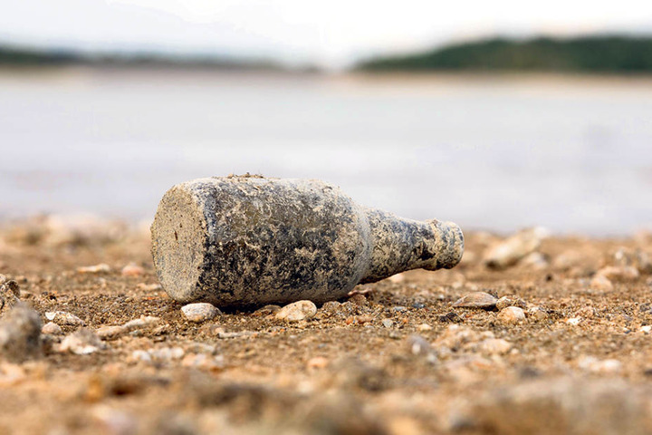 Auf dem Boden liegen Muscheln, Steine und alte Flaschen.